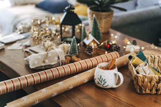 Preparing Christmas eco gift. Wrapping paper, wicker basket, coffee cup. Unprepared presents on wooden table with natural decor elements and items Christmas packing wrapping Concept.