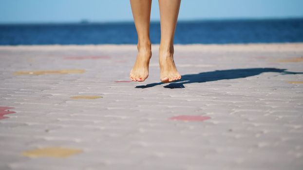 on the paving slabs, against the background of the sea, women's legs are dancing, barefoot. summer hot day. High quality photo