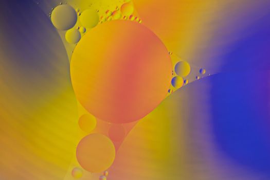 Colorful oil drops on water surface. Abstract blue yellow orange macro background