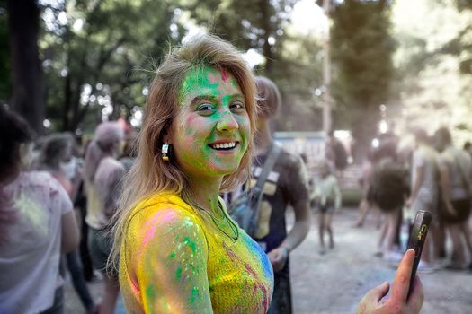 Young people, teenagers and adults celebrate the Holi event in Ukraine in Chernivtsi on March 8 in 2022. They have fun and throw paint at each other. High quality photo