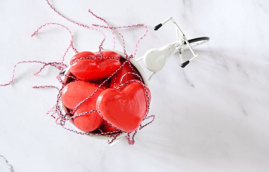 red toy hearts in the back of a white mini bike on a white wooden background Valentine's Day concept banner. High quality photo