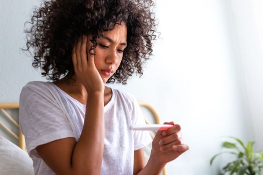 Sad multiracial young woman after seeing unexpected and unwanted pregnancy test result. Pregnancy.