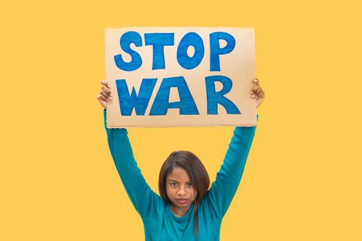 Girl holding stop war sign against yellow background. Isolated woman protest slogan. High quality photo