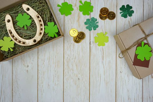 Items for St. Patrick's Day are laid out on a wooden background. Gifts for the celebration of St. Patrick. The horseshoe is in a box with fresh hay.