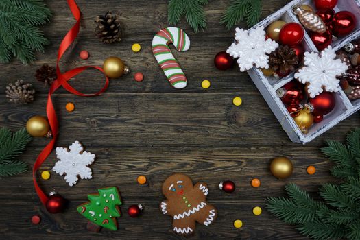 There is a Christmas decor on a wooden background. Christmas tree toys, gingerbread, lie on a wooden background.