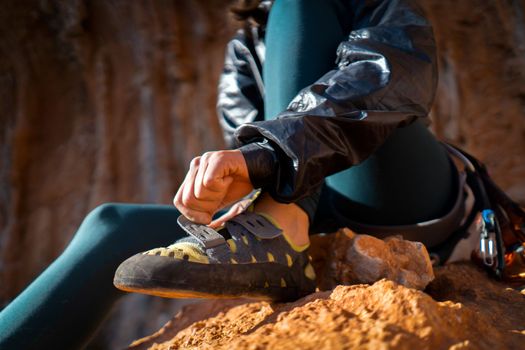 A young girl puts on special climbing shoes on her legs before climbing outdoor training, hands and feet close-up. A woman leads an active lifestyle, is involved in mountaineering and rock climbing.