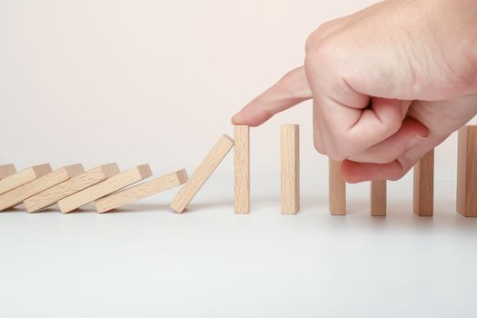 Hand stopping the Domino effect stopped by unique, Business Ideas