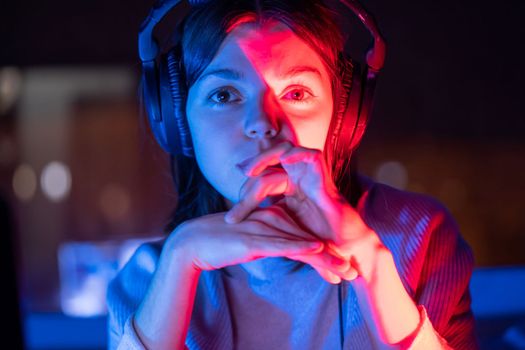 A young girl holds headphones and is listening and composing music, a woman sits with a laptop by the window in her room, works and enjoys the sound.