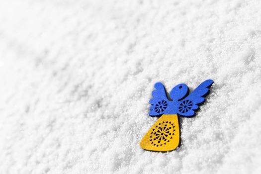 yellow blue wooden angel on snow, as symbol of support europe in winter. concept needs help and support, truth will win