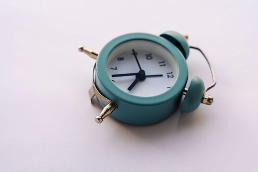 close-up of a small blue alarm clock in vintage style on a white background. The concept of passing time. Save time. deadline.