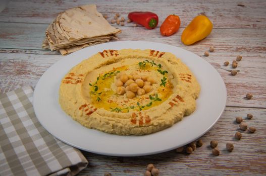 Homemade hummus with tahini plate with olive oil and paprika and pita isolated on brown background. High quality photo