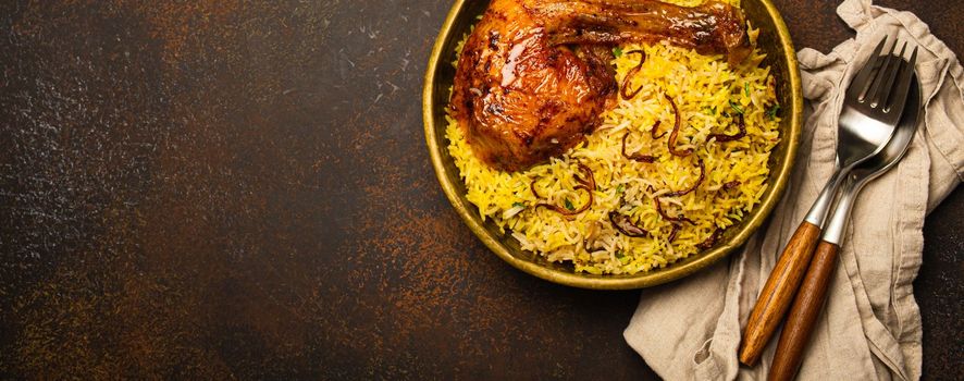 Delicious Indian dish Biryani chicken with basmati rice in metal brass old bowl on table dark rustic stone background. Traditional non-vegetarian food of India, top view with space for text