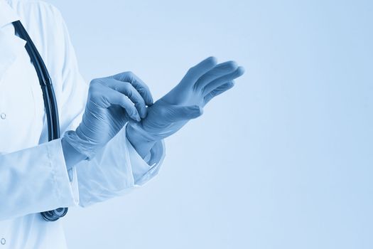 Close up of a female doctor putting latex gloves on a white background