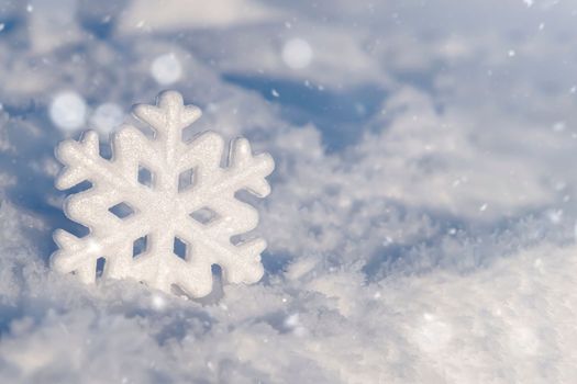 Christmas background with decorative snowflakes on snow. Christmas decoration on natural snow. A snowflake in the snow. Festive background for the design.