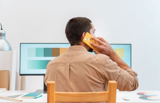 Young graphic designer sitting at his work desk and using a color palette to do an art project. High quality photo