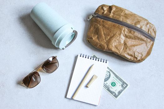 Pen, bag, cardboard cup made of recycled paper. Travel composition with sunglasses and dollars. Eco friendly modern objects from ecological biomaterials.