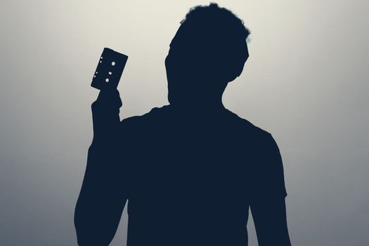 silhouette of young man with a retro cassette player, hears music