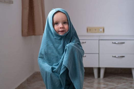 Cute caucasian baby girl dressing herself at her mother t-shirt.