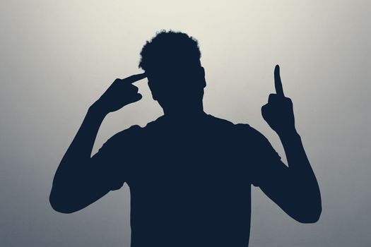 silhouette of man pointing upwards showing idea or eureka gesture generating interesting plan.