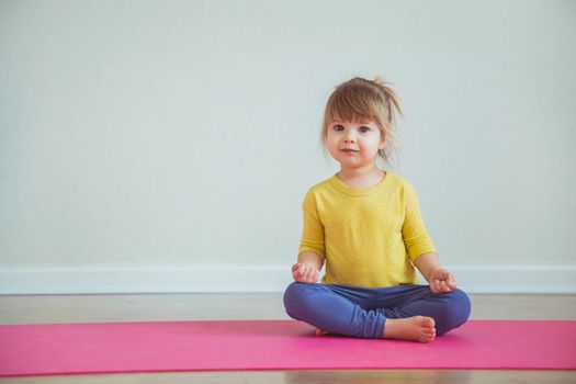 Charming baby doing yoga. Place for text.