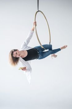 Caucasian female gymnast doing aerial hoop exercises and using smartphone