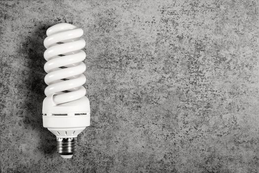 Luminescent spiral form lamp with E27 screw cap base on gray background with copy space.