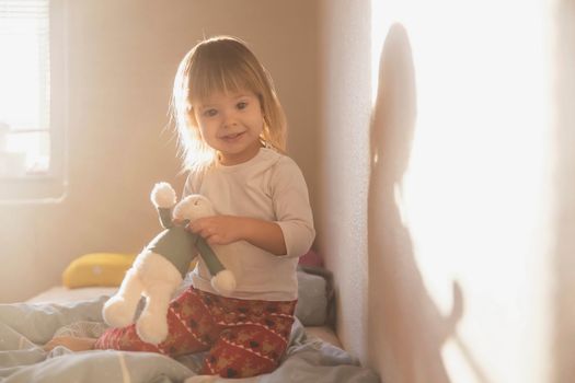 charming blonde baby with a toy in the morning.