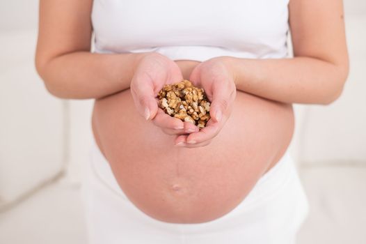 Pregnant woman holding a handful of walnuts