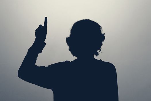 Unknown female person silhouette in studio pointing up giving advice