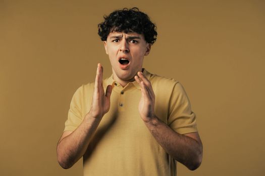 Frightened shocked man afraid of something and looks into camera with big eyes full of horror on yellow background. Phobia, trouble, panic concept. High quality photo