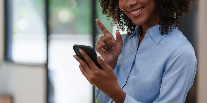 Business black woman having phone conversation with client in office. African american young woman using smart phone.