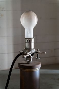 Old white bulb on the vintage metal holder with power wire