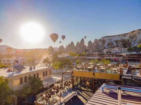 Colorful hot air balloons flying over at fairy chimneys valley in Nevsehir, Goreme, Cappadocia Turkey. Spectacular panoramic drone view of the underground city and ballooning tourism. High quality.