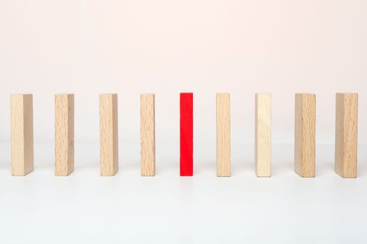 One red wooden block between the wooden block on white background. Be different concept.