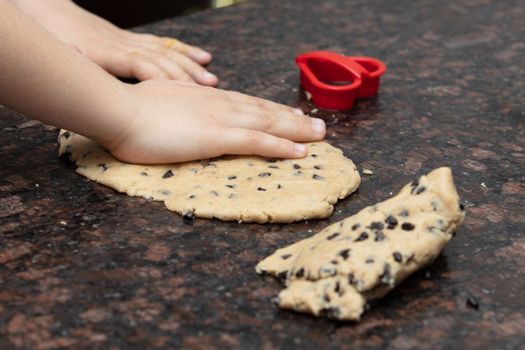 Kids baking cookies in house kitchen . Close-up child`s hands preparing cookies using cookie.