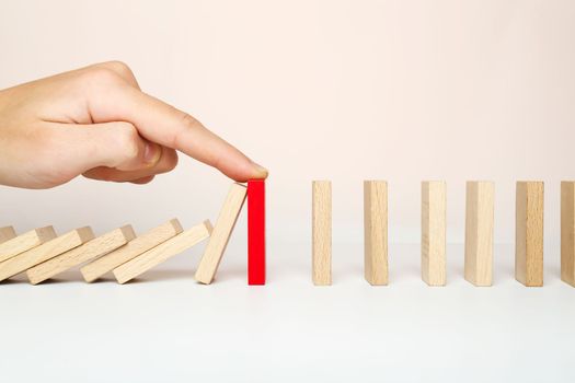 The domino falls, and the finger stops the chain reaction. The concept of solving the problem.