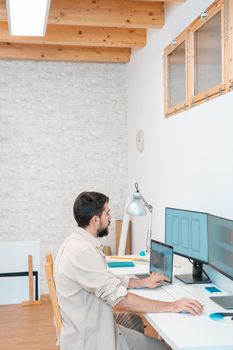 Vertical shot of a young entrepreneur working in his computer in a modern workspace office at home. Freelance guy starting small business. High quality photo