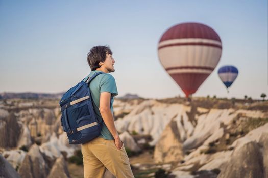 Tourist man looking at hot air balloons in Cappadocia, Turkey. Happy Travel in Turkey concept. Man on a mountain top enjoying wonderful view.