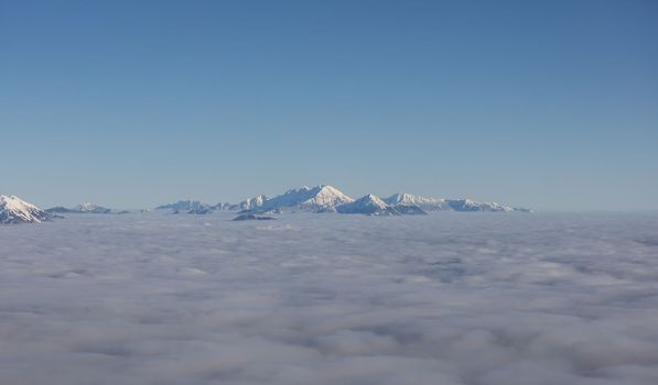 Winter mountains covered with snow landscape over clouds. High quality photo