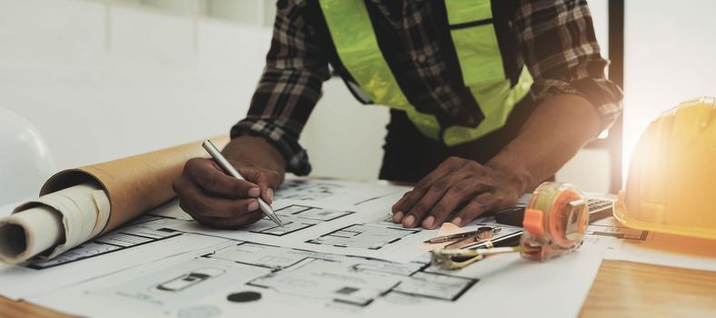 Close up of civil male engineer asian working on blueprint architectural project at construction site at desk in office