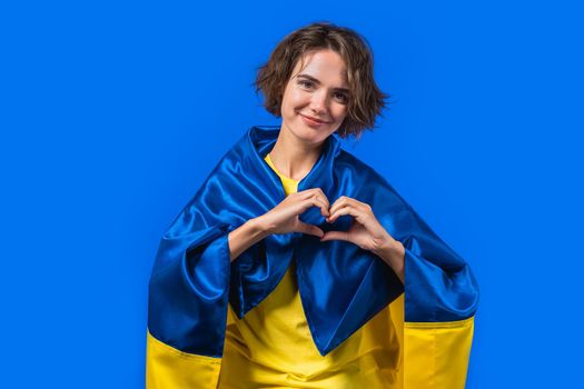 Woman with national Ukrainian flag showing sign of shape heart on yellow.Volunteering, charity donation, gratitude symbol,. High quality photo