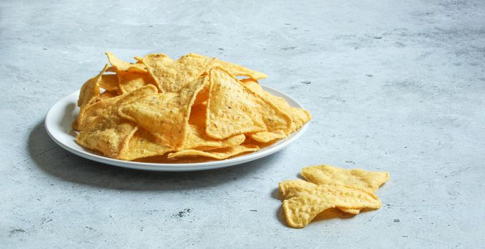 White plate with corn chips nachos on the grey concrete background. Mexican chips nachos.