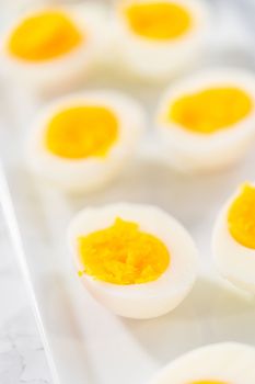 Sliced hard-boiled eggs on a white serving plate.