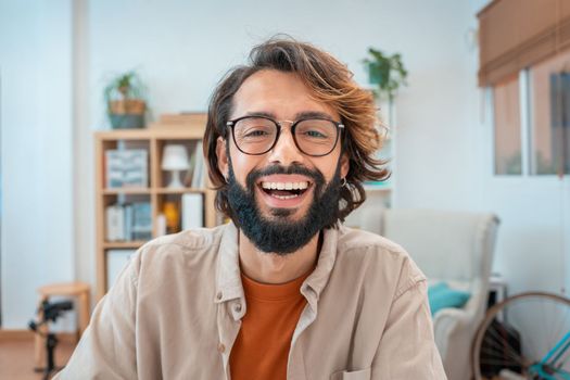 Portrait of a freelancer man at home office, looking and smiling at camera. Happy entrepreneur guy enjoying remote work and self-employment. High quality photo