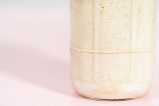 Feeding sourdough starter in a glass mason jar for baking artisan bread.