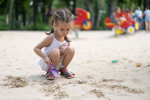 Little Girl Playing Sandbox Playground Digging Sand Shovel Building Sand Figure Summer Day. Caucasian Female Child 5 years Have Fun Outdoor