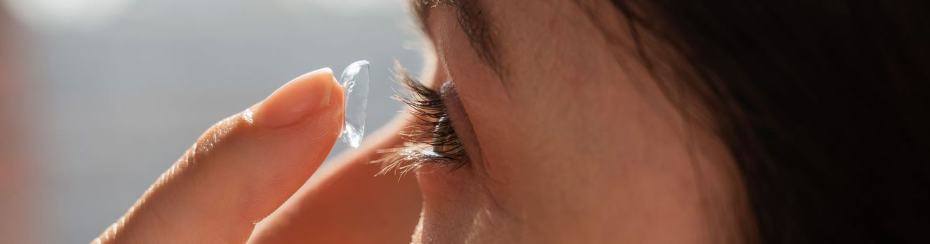Close-up portrait caucasian woman putting on a contact lens. Widescreen