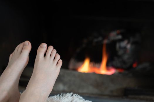 Barefoot boy warming his feet with firewood at home. Relax time , economical crisis concept.