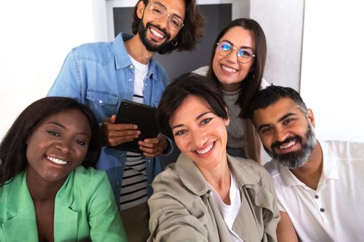 Group of smiling multiracial coworkers take selfie in the office. Social media and business concept.