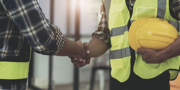 construction worker team hands shaking after consultation meeting to greeting start up plan new project contract in office center at construction site, teamwork, partnership and contractor concept..